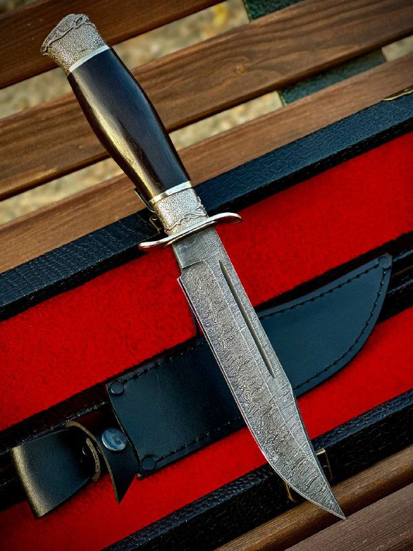 Рукоять ножа «Разведчик» из граба и украшенные мельхиоровые элементы, нож расположен в футляре на бархатистой подложке рядом с кожаными ножнами.