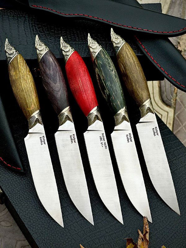 Крупный план ножей «Осётр»: видны мельхиоровые гарды, разные цвета рукоятей и аккуратно подогнанные кожаные ножны.