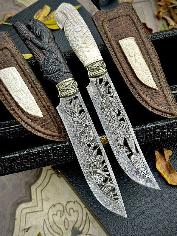 Вертикальная фотография пары ножей: вырезная резьба по клинку и рукояти, видны мельхиоровые детали и коричневые кожаные ножны.
