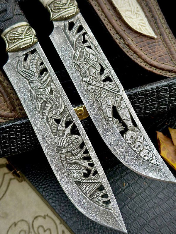 Близкий вид на орнамент и сюжетную резьбу по поверхности дамасских клинков; заметна тонкая текстура металла и художественные мотивы.
