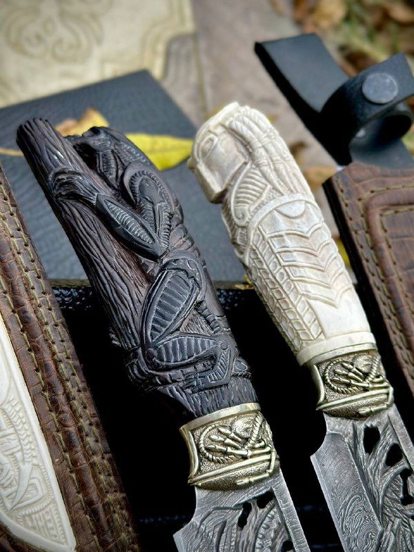 Рукояти ножей — тёмная и светлая — выполнены из граба с глубокой ручной резьбой, видны переходы к мельхиоровым украшениям.