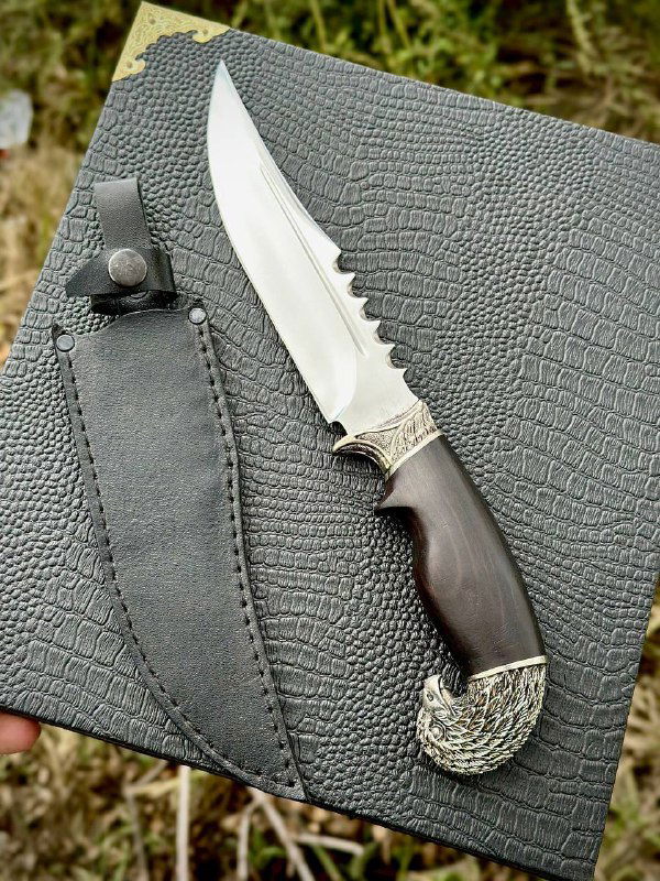 Разложенный нож «Орлан» и кожаные ножны: видно форму клинка, насечки на обухе и декоративную отделку рукояти из граба.