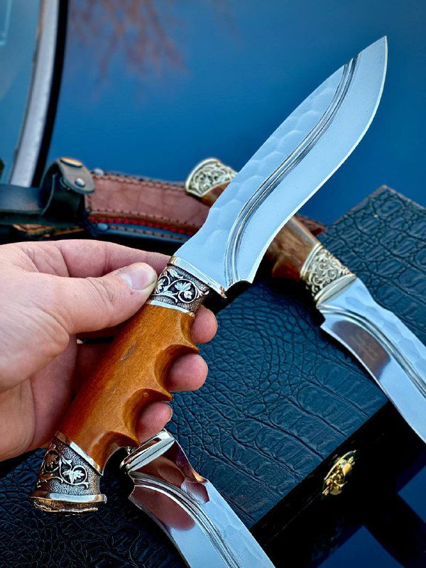 Рука держит нож с фигурной рукоятью: видно соотношение размера клинка и рукояти, честный обзор хватa и веса в руке.