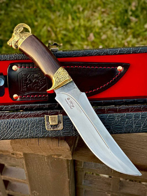 Нож «Тур» лежит на футляре с красной подкладкой: видно форму клинка, клеймо на лезвии и кожаные ножны рядом с рукоятью из граба.