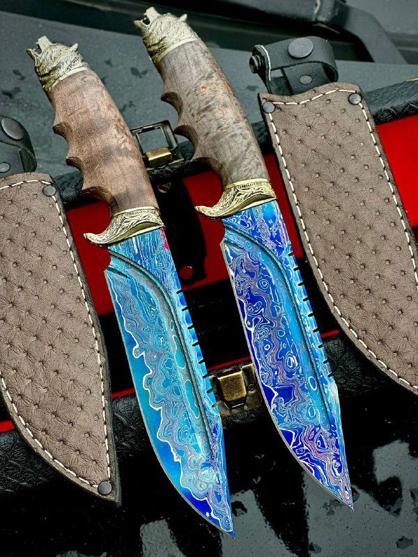 Две пары ножей с интенсивным синим и бирюзовым рисунком на лезвиях; показаны кожаные ножны и декоративные элементы на рукоятях из стабилизированной древесины.