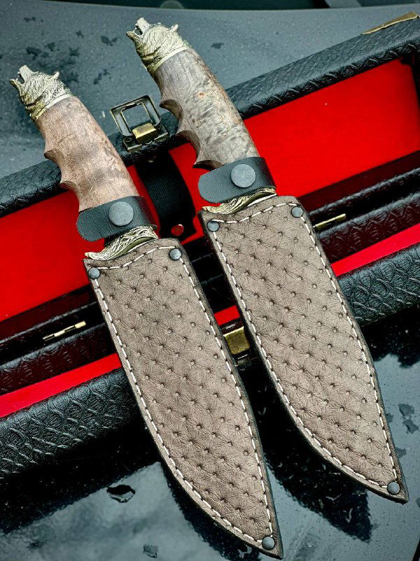 Два кожаных ножна размещены рядом на тёмной поверхности; показана текстура материала ножен и фрагменты рукоятей изделий из стабилизированной древесины.