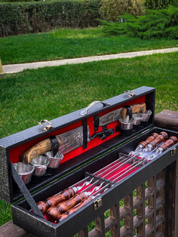 Крупный план раскрытого кейса с комплектом для шашлыка: шесть шампуров с деревянными ручками, разделочный нож и аксессуары аккуратно уложены в мягкую подкладку.