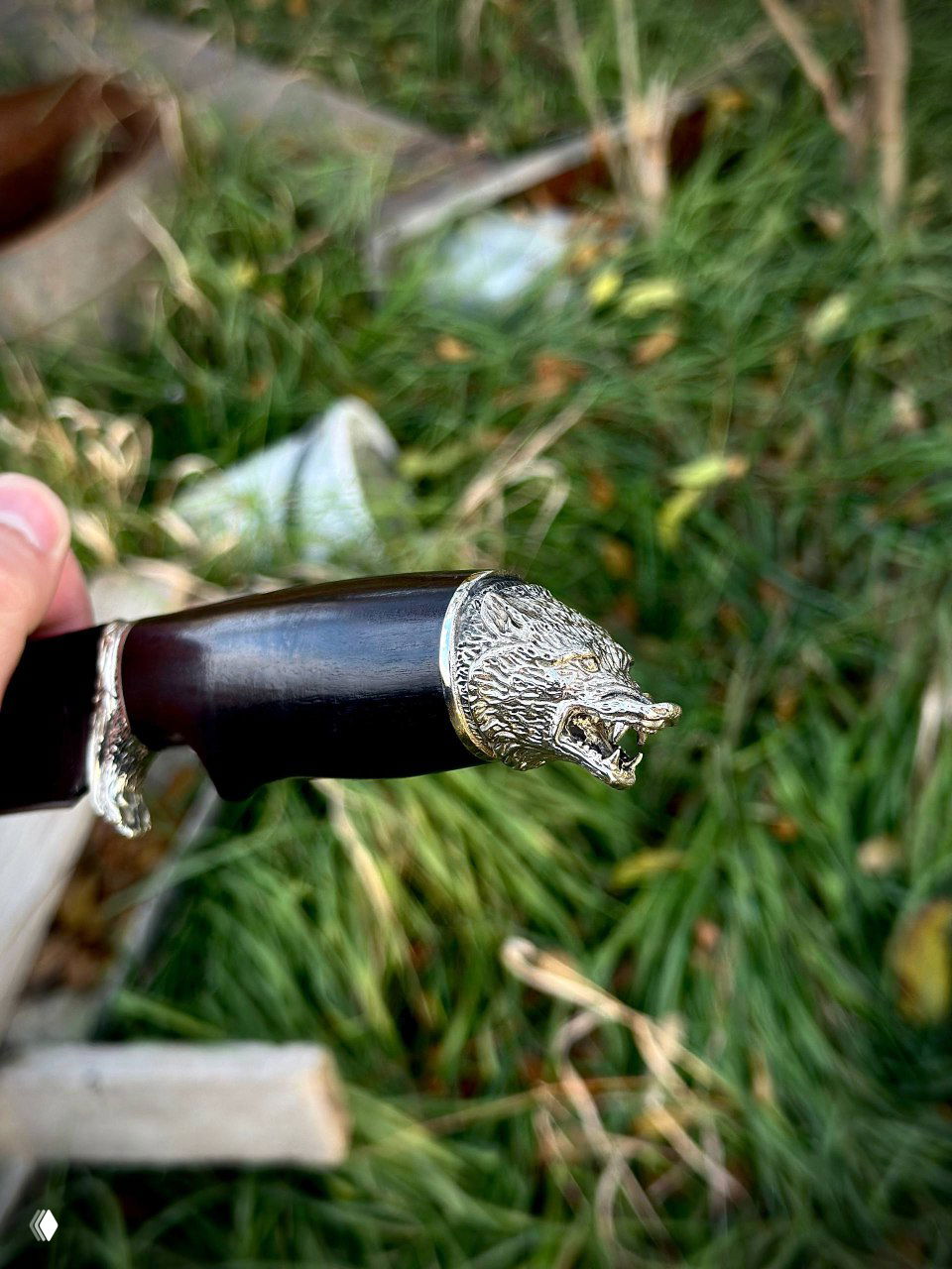 Деталь навершия рукояти ножа «Волк»: скульптурная голова волка из мельхиора, показанная крупным планом, подчёркивающая декоративную отделку изделия.