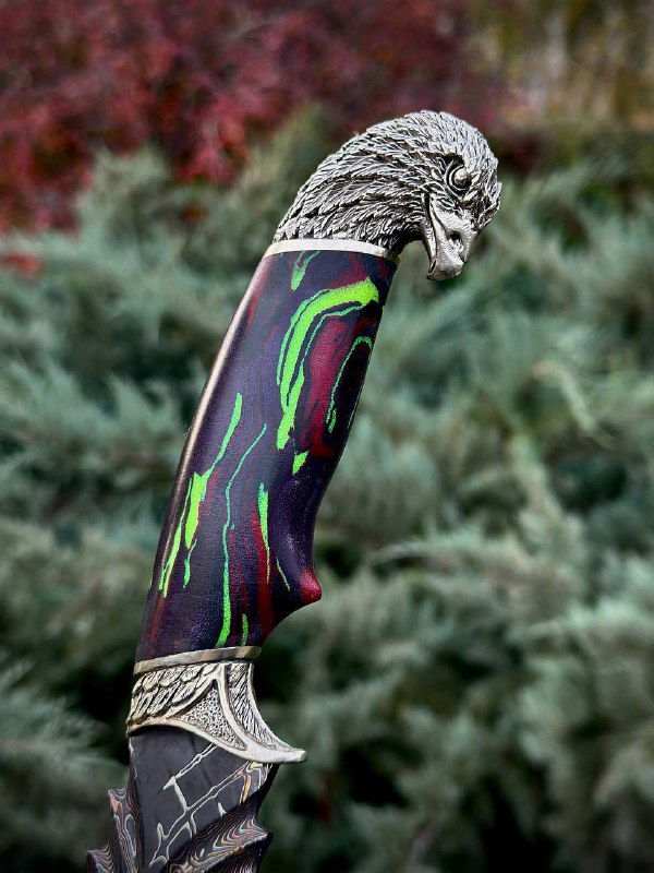 Деталь рукояти ножа «Орел»: декоративный навершие с изображением орла, контраст микарты и мельхиора на природном фоне.