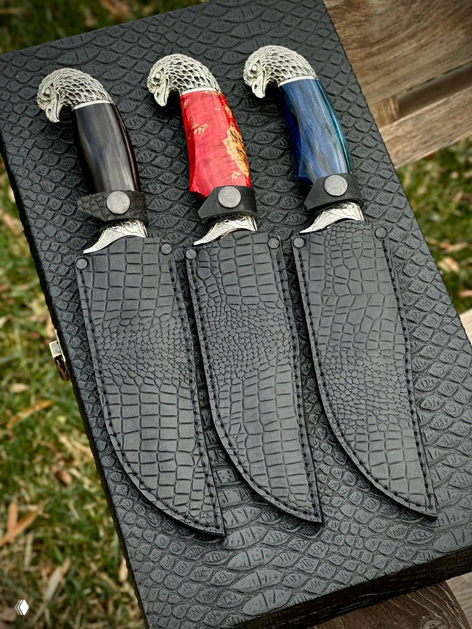 Три ножны из чёрной кожи рядом с ножами «Орлан»: аккуратная отделка, кожаные чехлы в комплекте для каждого ножа.