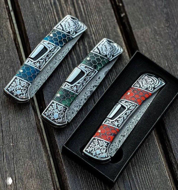 Три сложенных складных ножа с дамасскими клинками, рукоятями из акрила в виде сот и мельхиоровыми вставками, упакованные в подарочную коробку.