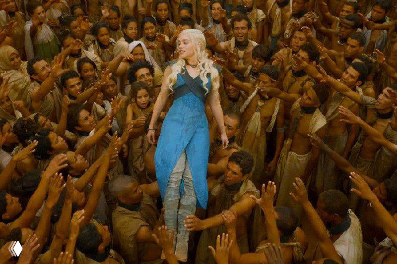 Женщина в синем платье среди плотной толпы, множество рук тянется к ней — сценическая иллюстрация давления, зависимости и внимания со стороны окружающих.