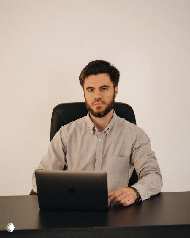 Человек за столом с ноутбуком в офисной обстановке: портретный снимок автора или иллюстрация к теме таргетированной рекламы и бизнеса в Telegram.