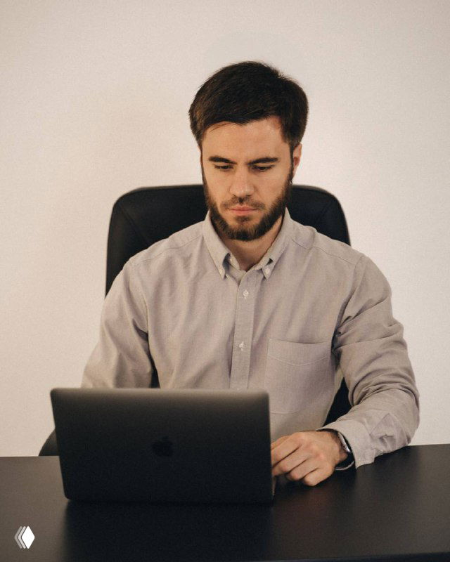 Мужчина в светлой рубашке за ноутбуком на столе, сосредоточенно работает; фото иллюстрирует тему рекламы и каналов.