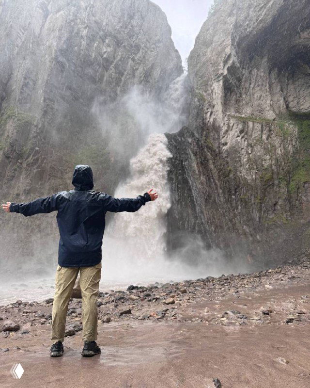 Человек в дождевике с расправленными руками на фоне мощного горного водопада — иллюстрация к посту о целевых подписчиках в Telegram.