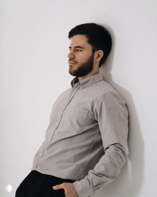 Портрет мужчины в рубашке и наушнике, опёршегося о стену и смотрящего в сторону; нейтральный фон, иллюстрация к посту о маркетинге.