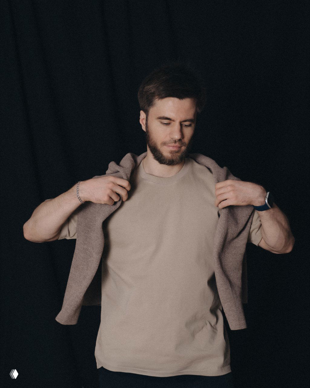 Студийный портрет мужчины в нейтральной футболке с накинутым свитером на тёмном фоне, иллюстрация к заметке про автономность бизнеса.