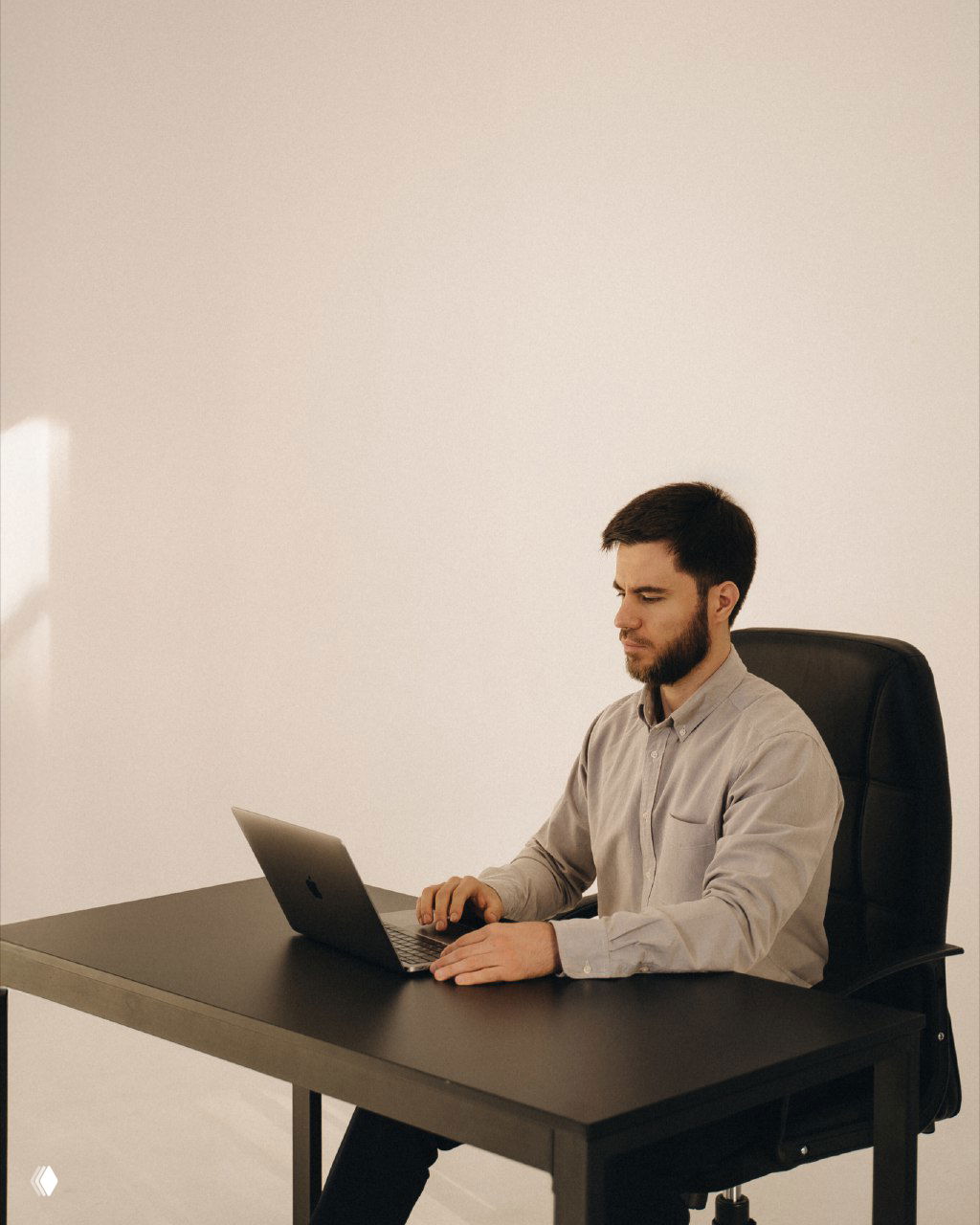 Мужчина за рабочим столом и ноутбуком в спокойной офисной обстановке — визуал для поста про настройку трафика и воронок в Telegram Ads, показывающий рабочего специалиста.