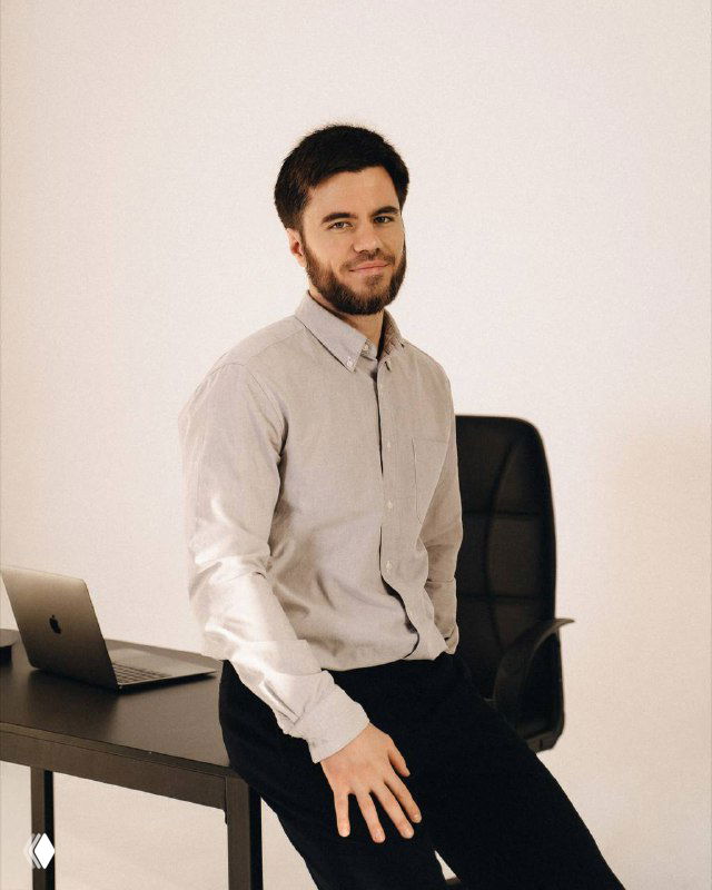 Мужчина сидит за столом с ноутбуком в минималистичном офисе — портрет, иллюстрирующий шпаргалку по маркетингу и нишам.