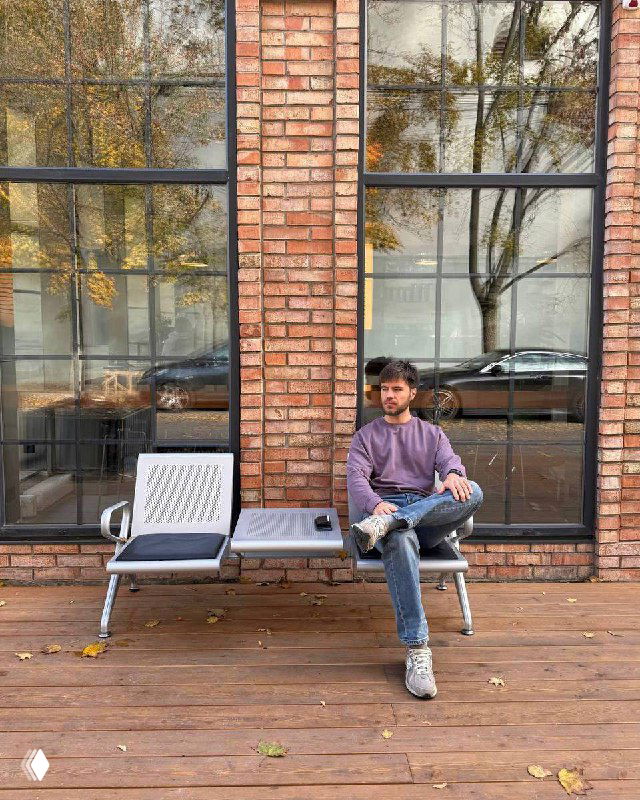 Человек сидит на скамейке у кирпичного фасада в городской среде; фотография иллюстрирует автора или кейс о закупках в Telegram и разбирательствах с админами