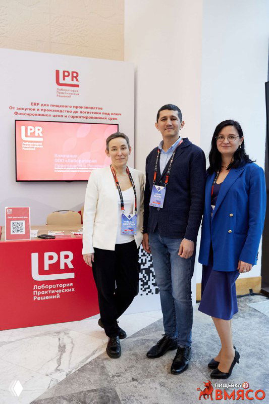 Три сотрудника ЛПР у выставочной стойки: деловое фото в фойе конференции Пищёвка3D с логотипом компании и экраном с презентацией.