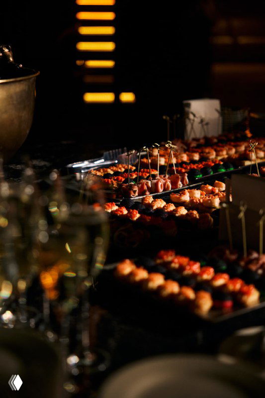 Кейтеринг и канапе в фокусе на фоне приглушённого света: закуски, сервировка и элементы фуршета для гостей Meat Night в зале мероприятия.