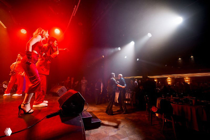 Артисты на сцене в динамичном выступлении под красно-белую подсветку: танцы и аплодисменты публики во время финального номера Meat Night.