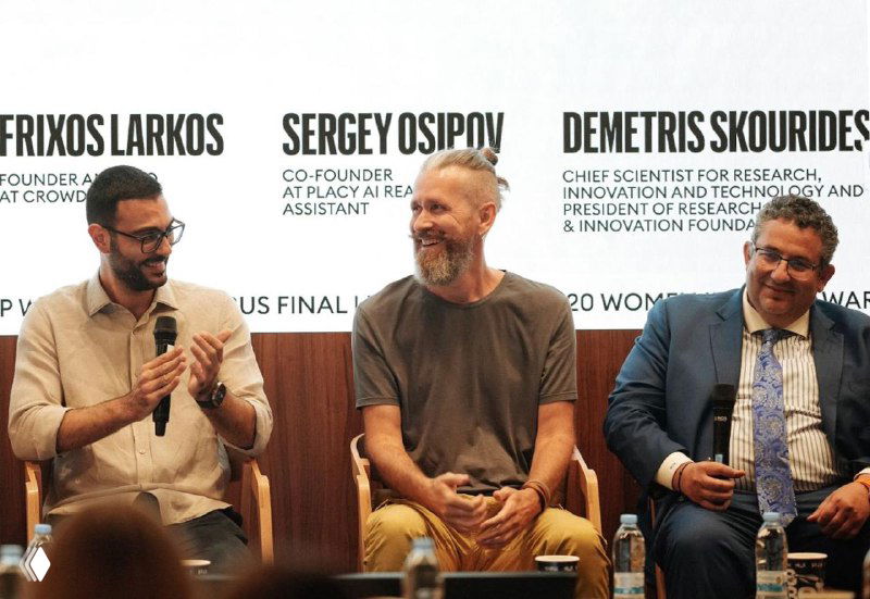 Photograph of three panelists seated on stage at a conference; Sergey Osipov (center) discussing Placy AI and proptech.