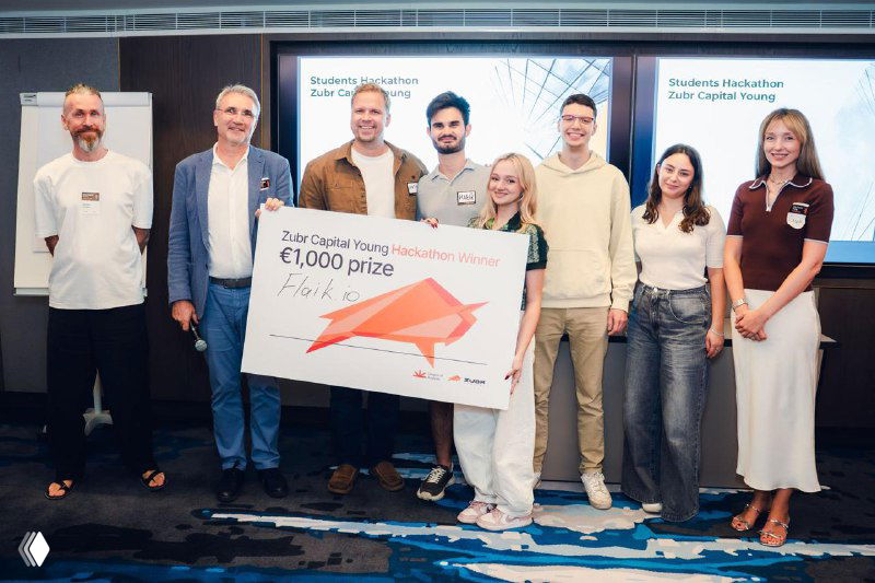 Winning team and organizers posing with a large prize cheque on stage: smiling founders, mentors and investors celebrating the hackathon results.