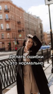 Женщина в пальто на городской улице у перил, поправляет волосы; на фото видны здания на заднем плане и надпись «Делать ошибки это нормально».