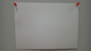 Прямоугольный белый лист бумаги, прикреплённый двумя красными кнопками к светло‑серой стене; ракурс показывает текстуру стены и лёгкую тень вокруг листа.