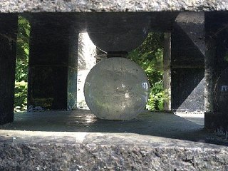 Небольшая прозрачная сфера, защищённая между бетонными элементами, вероятно, малая модель спутника или декоративный элемент инсталляции.