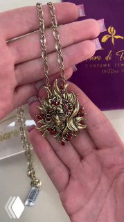 Крупный план кулона и цепочки FUOCO в руке: видно фактуру цепочки, подвеску с красными акцентами и бирку магазина Rosone.