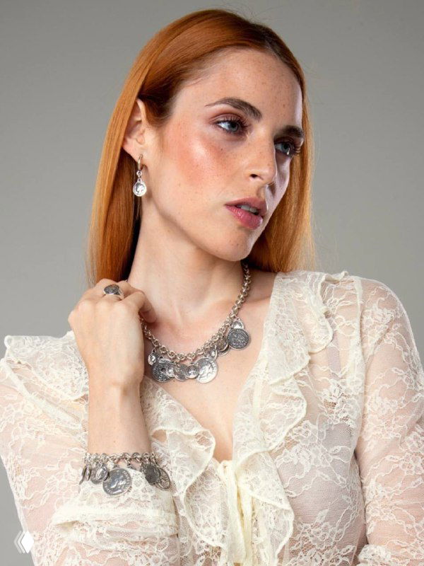 Модель в светлом платье демонстрирует серебристое колье и кольца из коллекции CICLON в студийной съёмке, акцент на деталях украшений