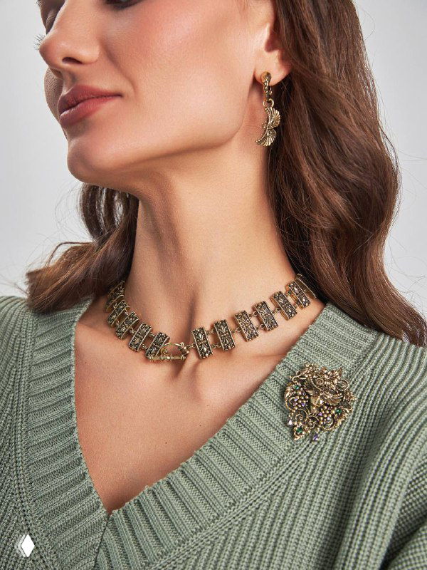 Широкий план шеи и декольте модели с металлическим чокером и брошей‑подвеской, демонстрирующие трансформируемый характер украшений Fiore di Firenze.