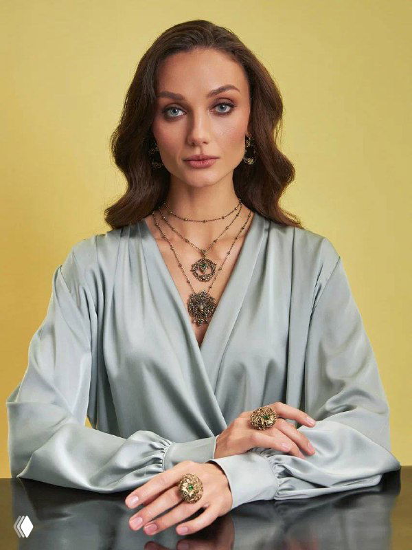 Полнотелый портрет модели в светлом платье с несколькими подвесками и кольцами, демонстрация общего образа и вечернего стилизованного лука с украшениями.