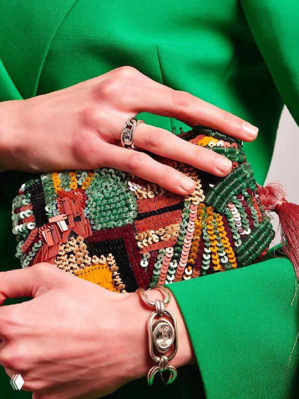 Крупный план женских рук в зелёном пиджаке с кольцами и браслетом, показ деталей и текстуры бижутерии CICLON в студийном кадре
