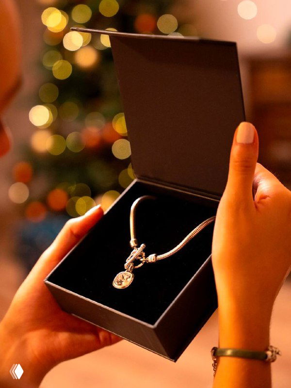 Руки открывают подарочную коробку с браслетом внутри — праздничная сцена, подчёркивающая идею подарка и упаковки украшений CICLON