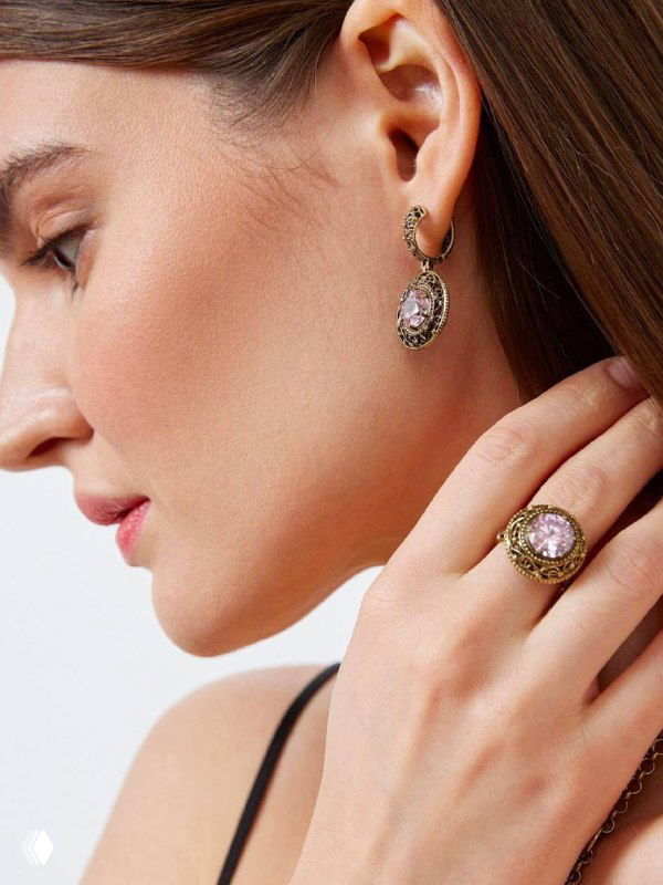 Профиль модели с длинными серьгами и крупным кольцом, естественный макияж и гладкая укладка волос, рекламный кадр с акцентом на украшениях.