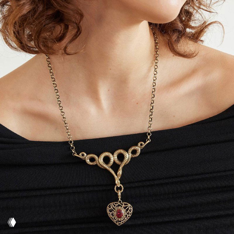 Модель в колье AMORE ETERNO: золотистая подвеска на шее на фоне тёмной одежды — пример того, как украшение смотрится в образе.