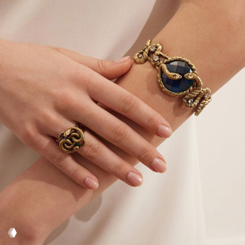 Рука модели с браслетом SERPENTI и кольцом в змеиной стилистике, демонстрация комплекта украшений и сочетания текстур золота и камня.