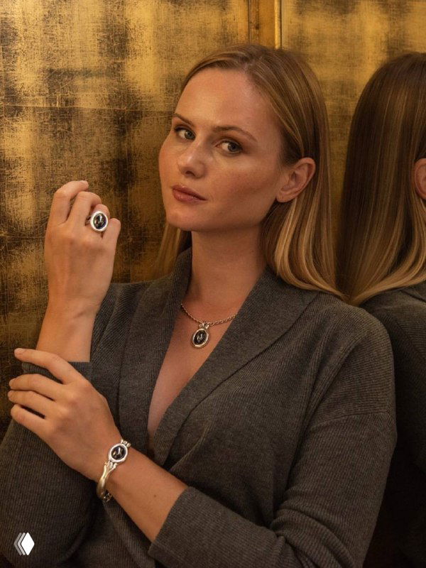 Модель в сером наряде демонстрирует кольцо и браслет CICLON; внимание на минималистичных формах и сочетании матового и глянцевого покрытия.