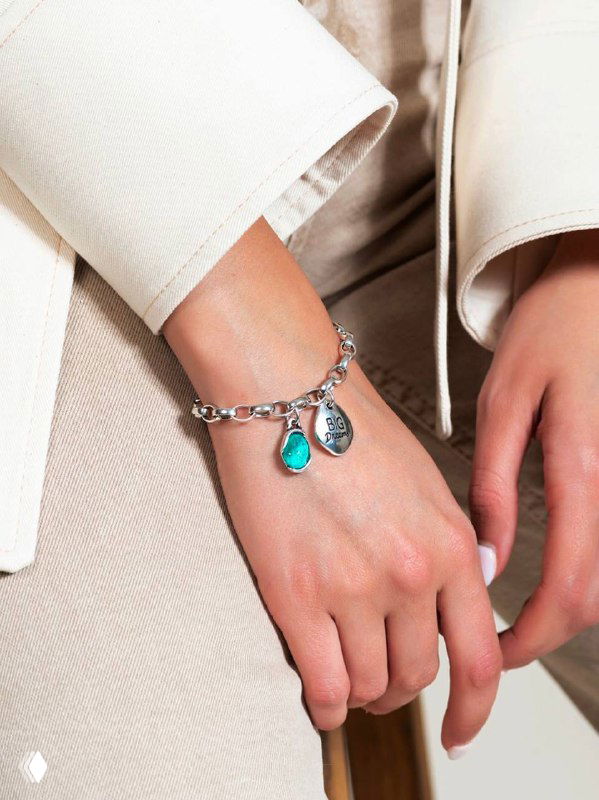 Крупный план руки в светлом пиджаке с браслетом CICLON и бирюзовой каплевидной подвеской; демонстрация цветового акцента в коллекции.