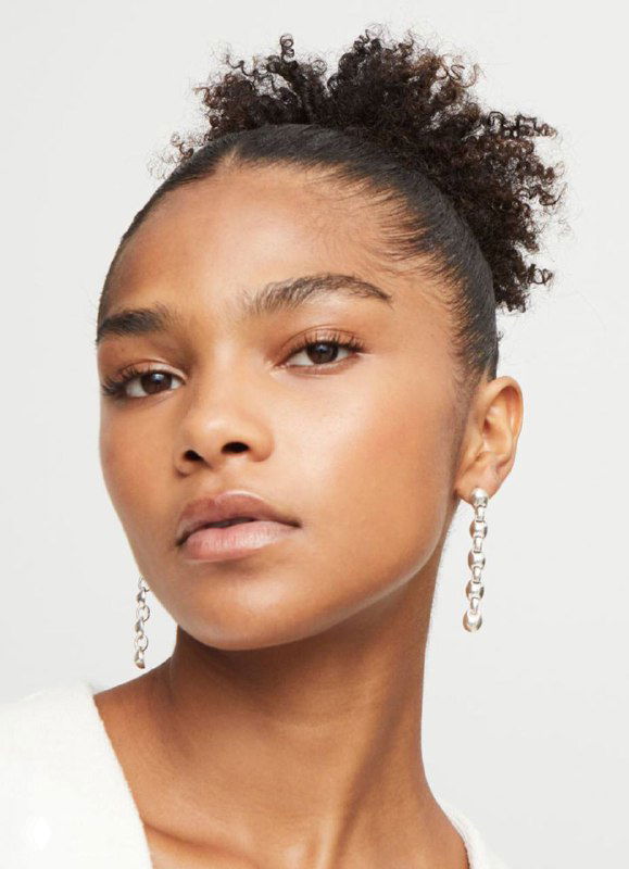 Модель в крупные серьги UNOde50 из коллекции Ser Intrepida с круглыми полусферами и кожаными вставками, студийная съемка.