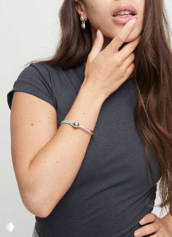 Женщина в браслете UNOde50 из коллекции Ser Intrepida: металлическая деталь и кожаная вставка крупным планом, портретный кадр.