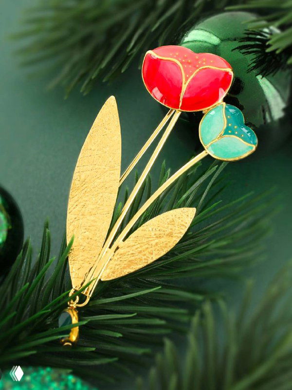 Брошь TARATATA в виде цветка с золотым покрытием и эмалью, аккуратно размещённая на зелёной праздничной ветке — художественная презентация изделия.