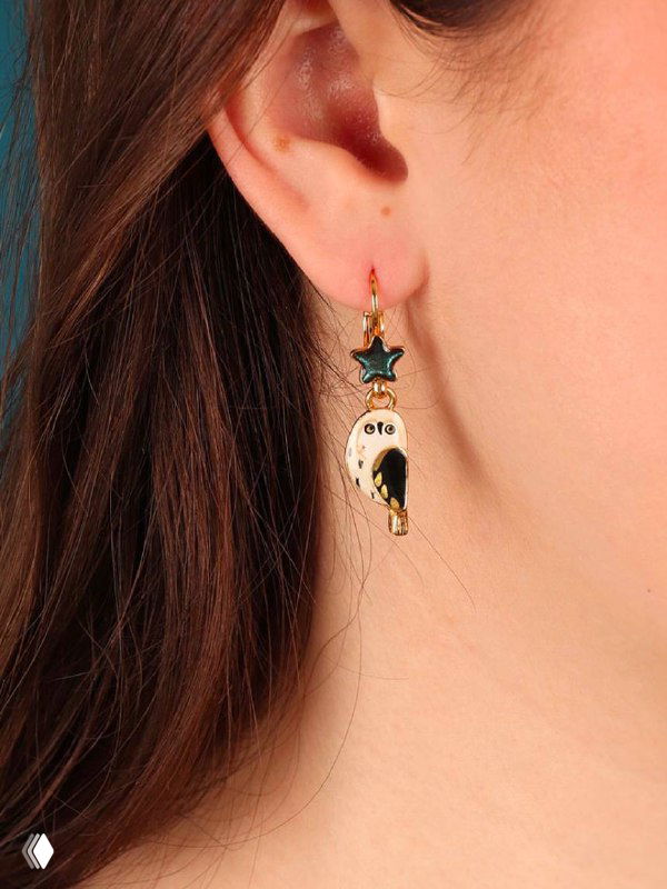 Серьги TARATATA на ухе модели: крупный кадр демонстрирует форму, цветную эмаль и золотое покрытие украшения в реальной посадке.