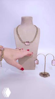 Манекен с ожерельем Claudio Canzian с крупным розовым камнем; рядом сопутствующие украшения и рука с красным маникюром для показа деталей.