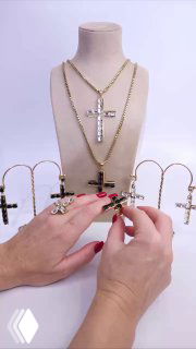 Два золотых ожерелья и кресты на манекене, детали коллекции Claudio Canzian; продавец корректирует композицию украшений рукой в кадре.