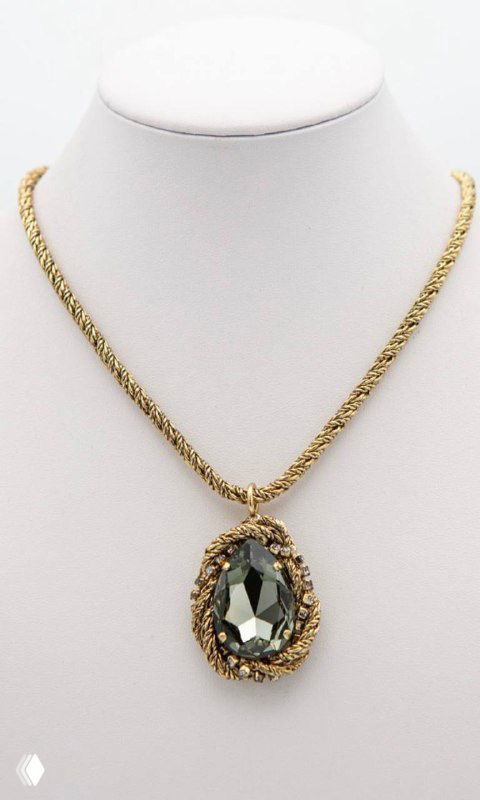 Подвеска Claudio Canzian на белом манекене: золотая цепочка в косичку и крупная каплевидная кристаллическая вставка на ней, студийный фон.